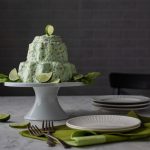Lime Jello Salad on a cake stand with limes and lettuce as garnish