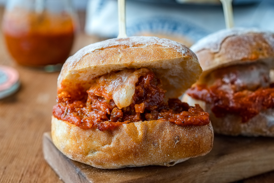 Porcupine Meatball Sliders sitting on a small cutting board with more sliders in the background.