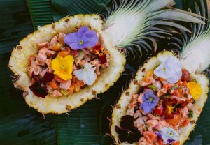 sinigang poke served in the pineapple halves with edible flowers on banana leaves