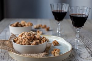 Candied Swedish Nuts in a white bowl with wine in the background.